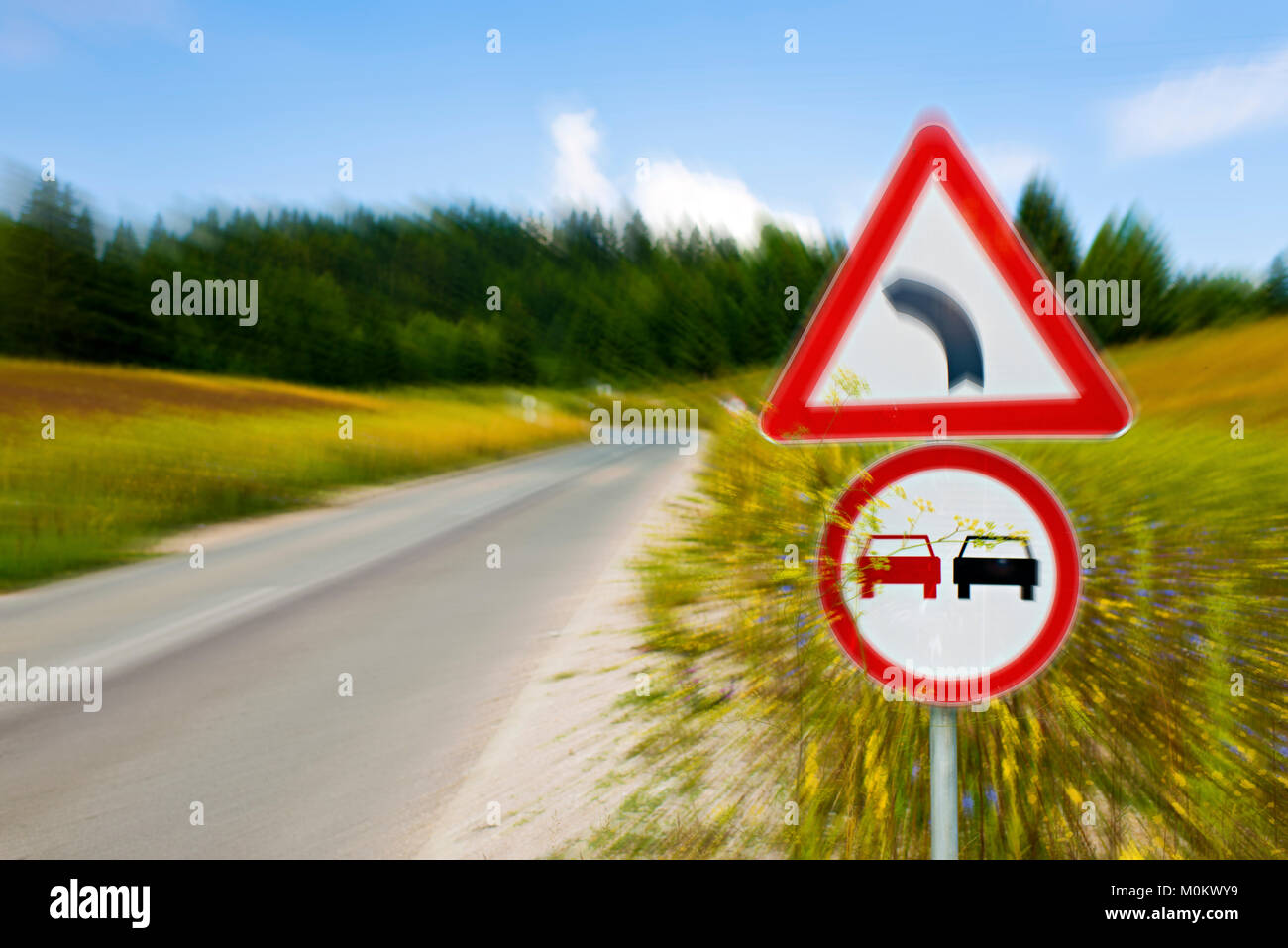 Segni di traffico su un countryroad attraverso una montagna di prato Foto Stock