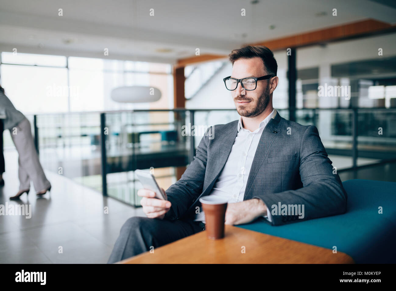 Pensieroso giovane imprenditore nel cafe usando il telefono Foto Stock