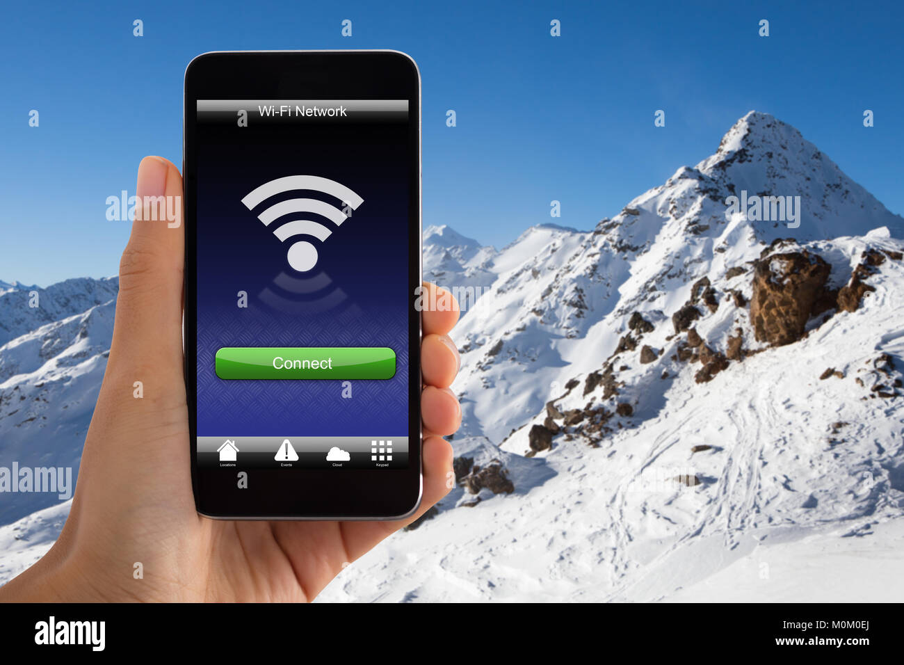Close-up della mano che tiene il telefono cellulare con il segnale wi-fi in Montagna innevata Foto Stock