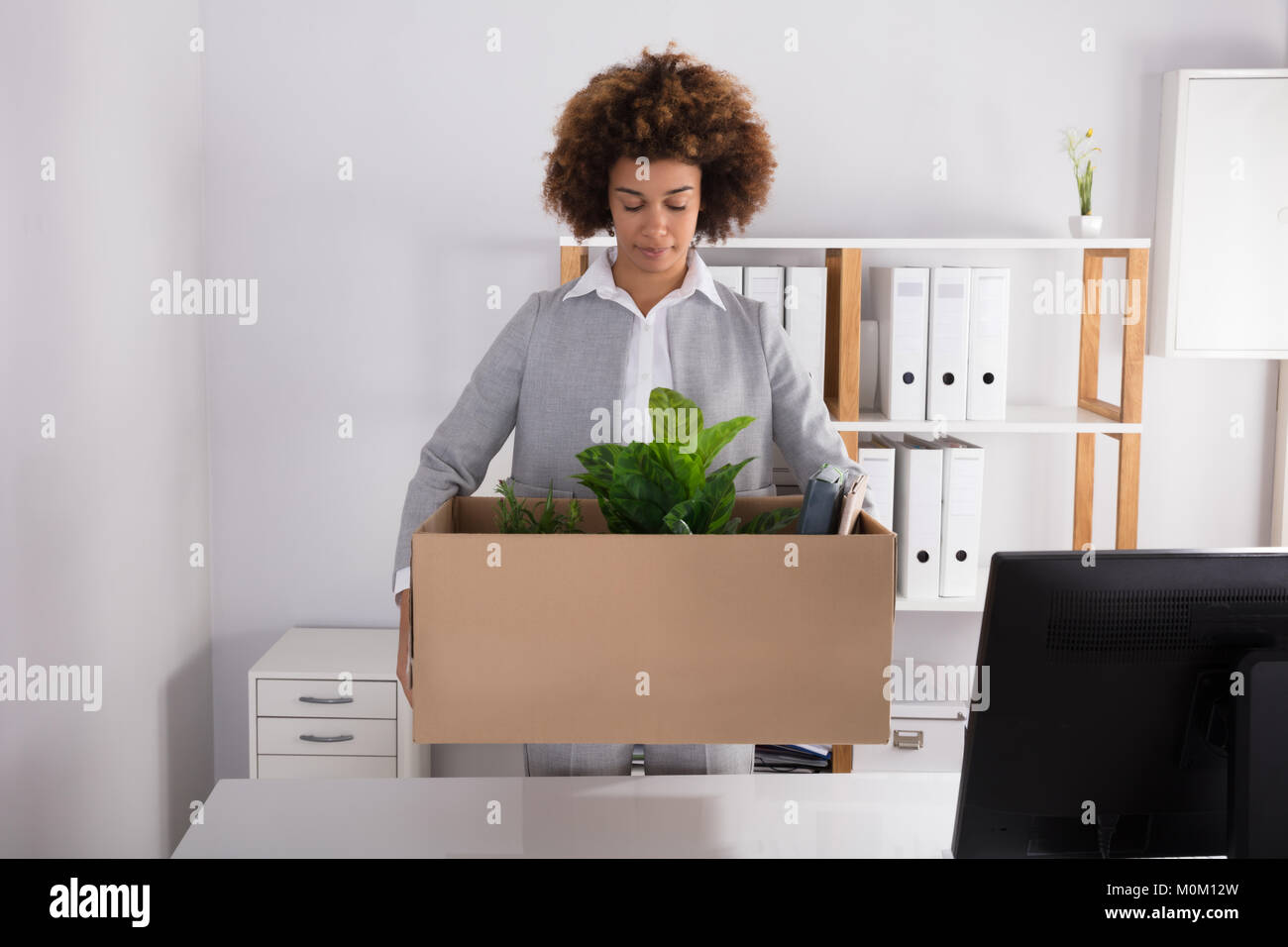 Giovane imprenditrice che porta una scatola di cartone con gli effetti personali al lavoro Foto Stock