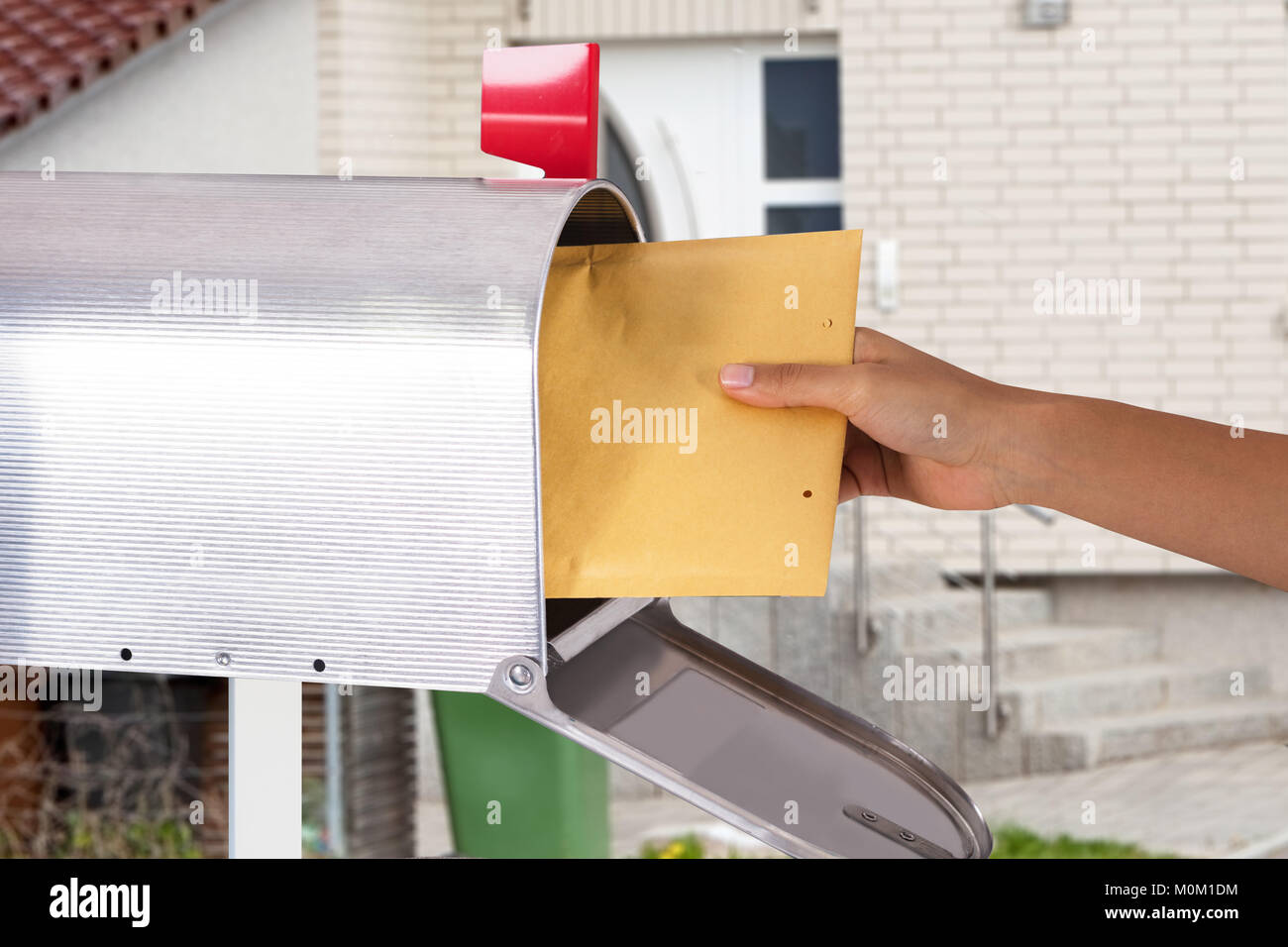Close-up di mano di una persona rimozione lettera dalla cassetta postale di argento Foto Stock