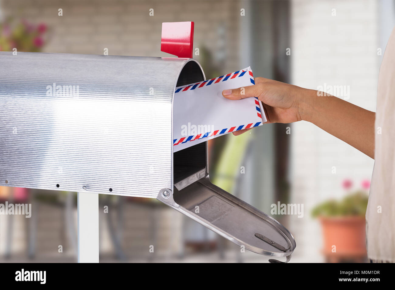 Close-up di mano di una persona rimozione lettera dalla cassetta postale di argento Foto Stock