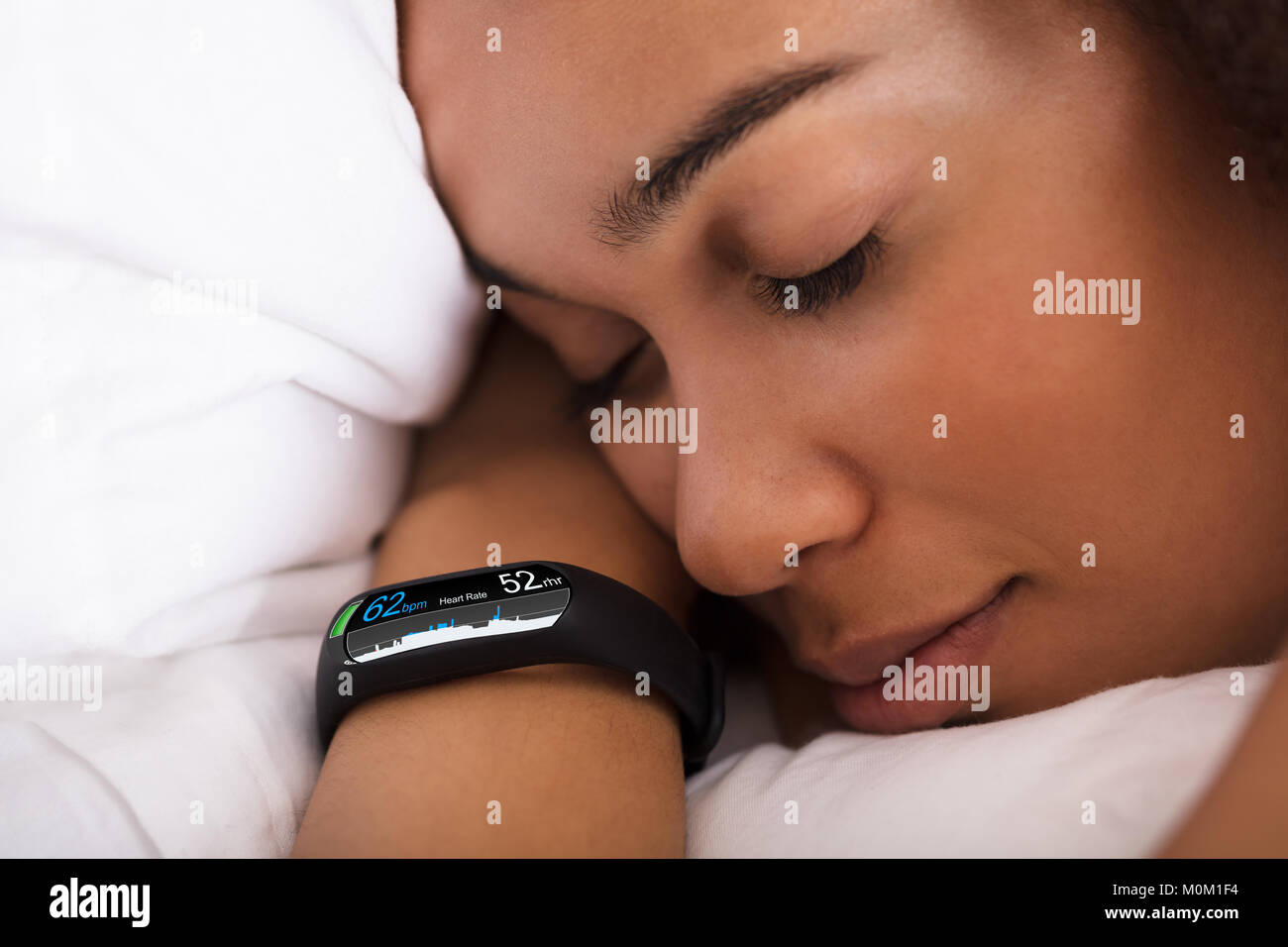 Close-up di donna che dorme sul letto con Smartwatch che mostra la frequenza cardiaca Foto Stock