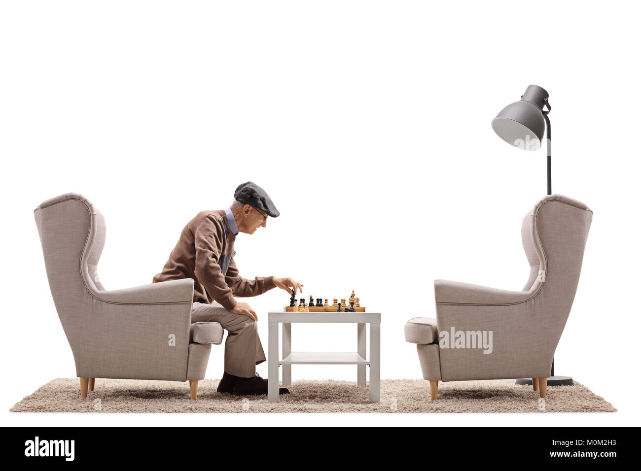 Senior seduto in poltrona a giocare a scacchi da lui stesso isolato su sfondo bianco Foto Stock