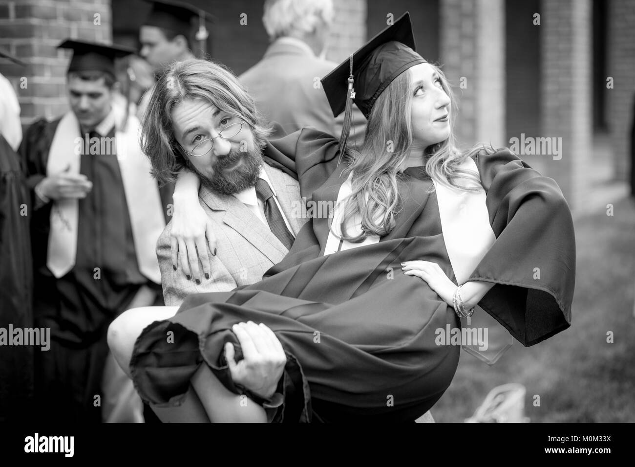 Giovane uomo barbuto mantiene giovane femmina graduate nelle sue braccia, College Park, Maryland Foto Stock