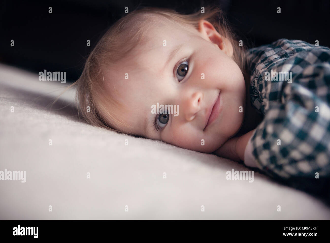 Il Toddler girl sdraiato sul pavimento e guardando la fotocamera Foto Stock