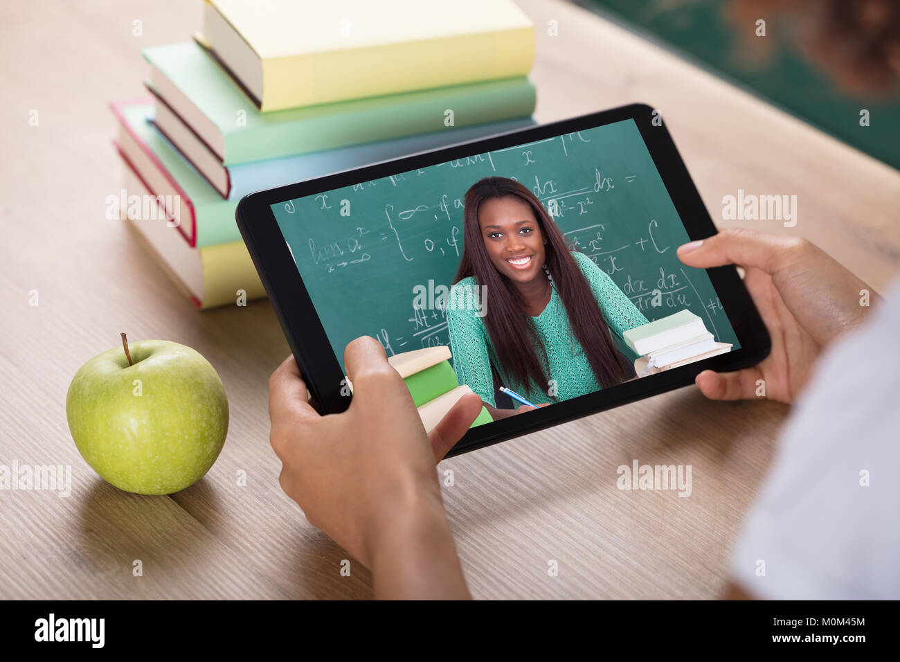 Studente la mano una videoconferenza con insegnante femminile sulla tavoletta digitale Foto Stock