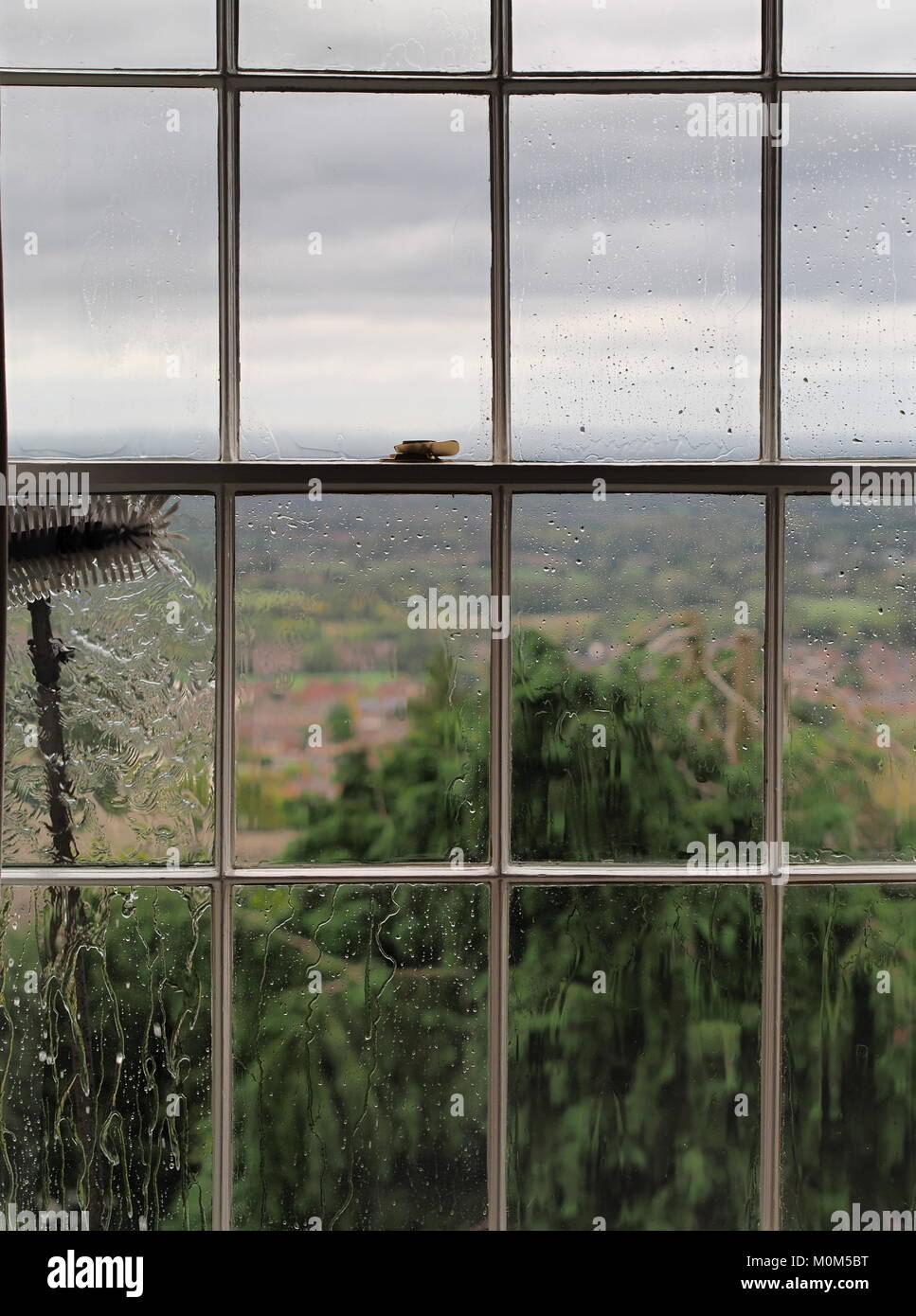 La pulizia in alto in vecchio stile finestre a ghigliottina con una spazzola telescopica Foto Stock