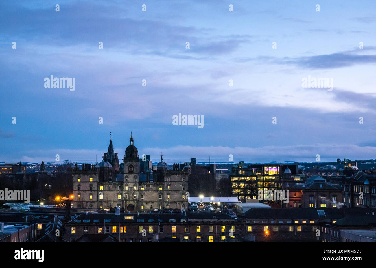 Vista dal castello di Edimburgo esplanade turrito del xvii secolo George Heriots scuola e di notte le luci del centro di Edimburgo, Scozia, Regno Unito al crepuscolo Foto Stock