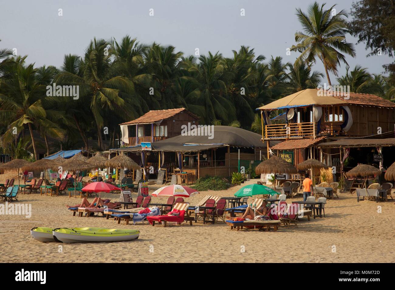 L'India,Goa,Patnem beach,i turisti sdraiati sui lettini nella spiaggia di sabbia dorata rivestita con alberi di noce di cocco,vicino Palolem Foto Stock