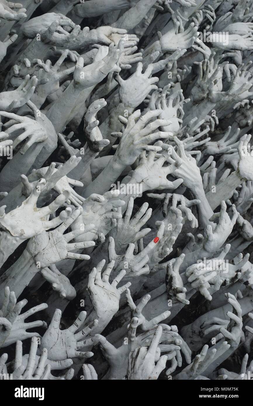 Armonici di sculture di una moltitudine di mani fino a raggiungere il cielo di fronte il bianco tempio Wat Rong Khun in Chiang Rai, Thailandia. Foto Stock