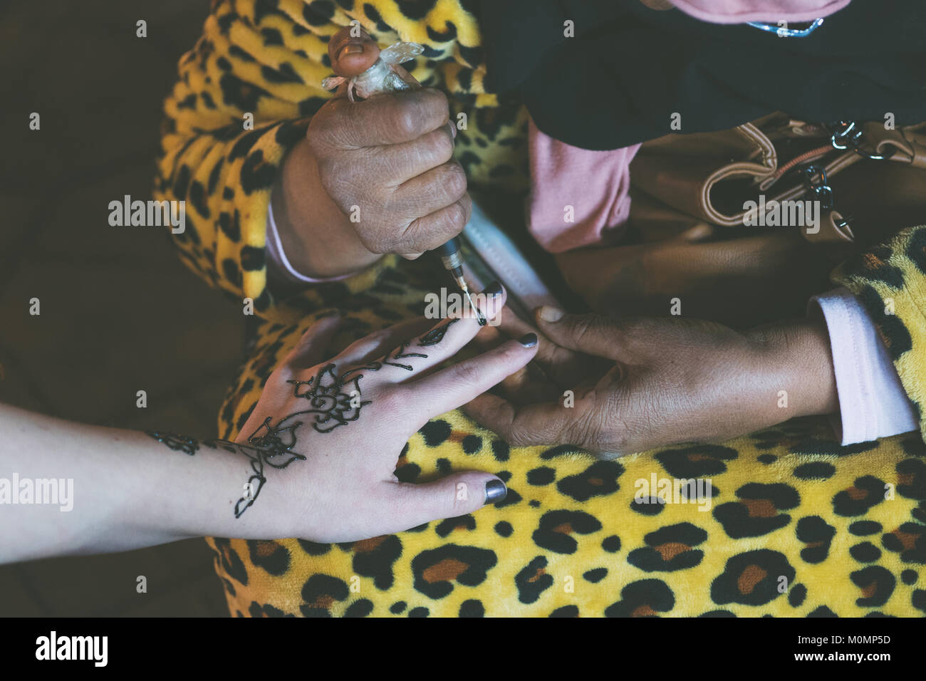 Donna musulmana sta facendo una temporanea henna tattoo su una mano della ragazza di colore bianco Foto Stock