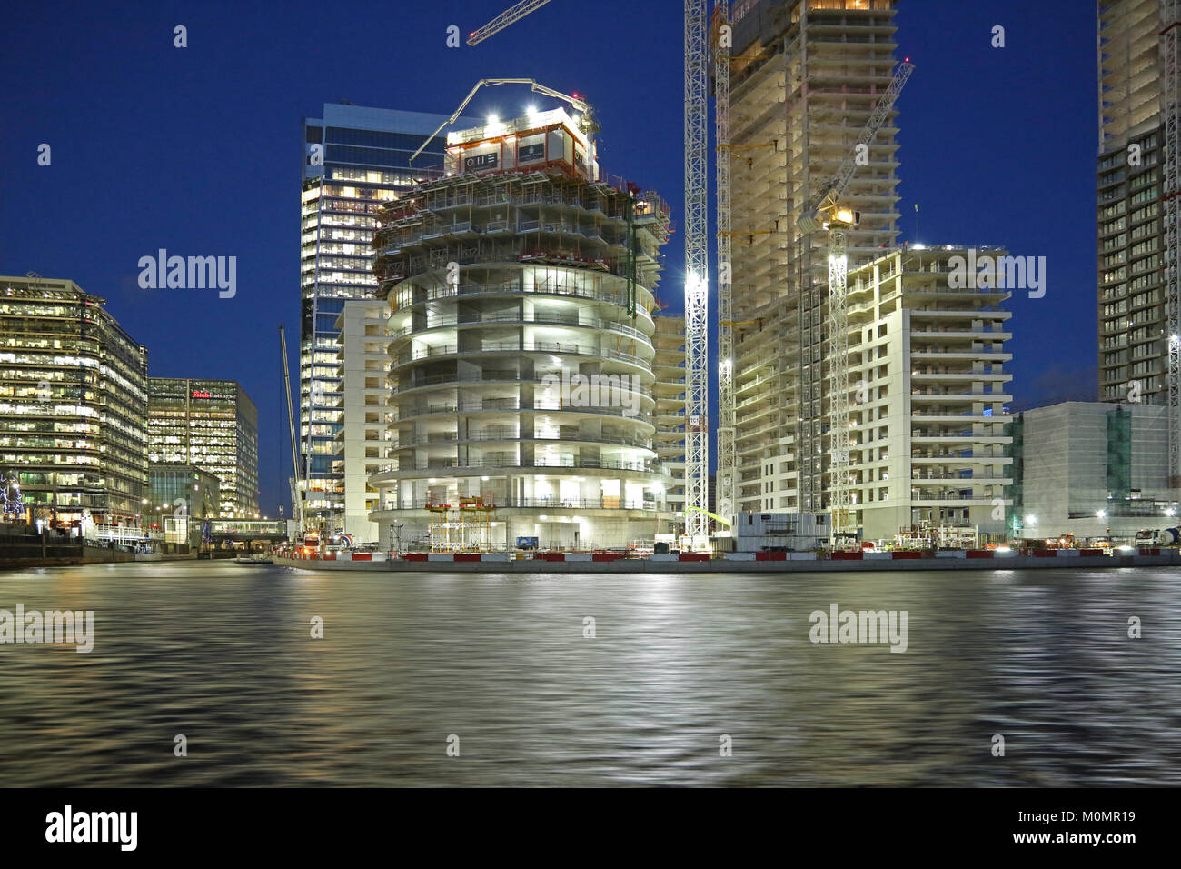 Vista del tramonto della costruzione di nuove torri residenziali in London Canary Wharf district. Mostra un parco auto sviluppo nel centro. Foto Stock