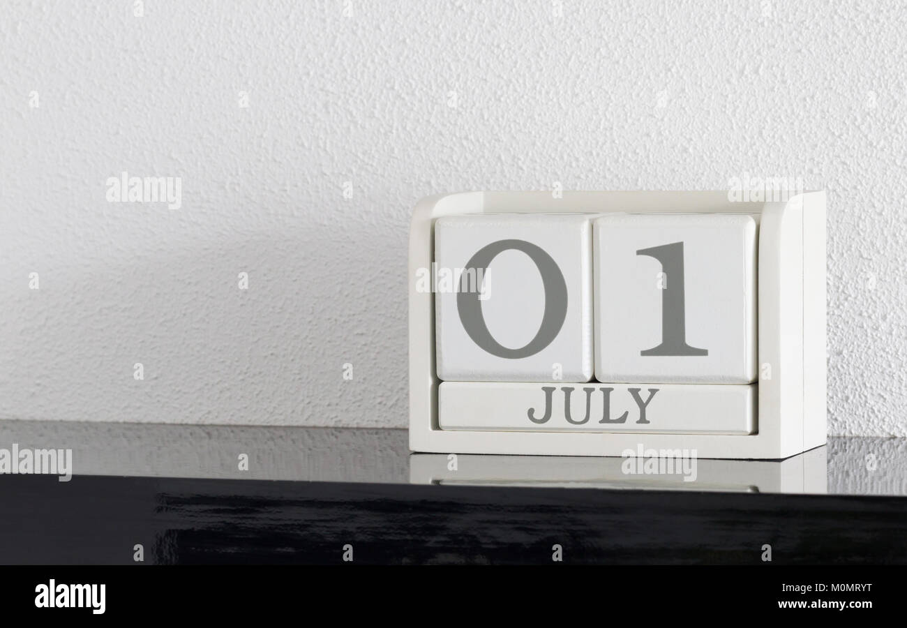 Block Bianco calendario data presente 1 e il mese di luglio sul muro bianco sullo sfondo Foto Stock