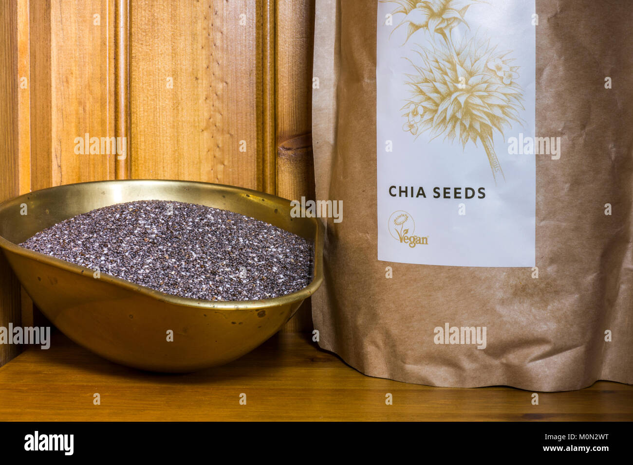 Chia (semi di salvia hispanica). Organico, non cotte, alto in proteina, vegan, super. In un pacchetto e una pesatura scoop su un ripiano in un armadio di pino. Foto Stock