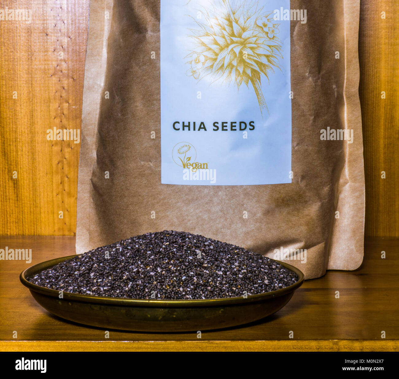 Chia (semi di salvia hispanica). Organico, non cotte, alto in proteina, vegan, super. In un pacchetto e su un vassoio di pesatura su un ripiano in un armadio di pino. Foto Stock