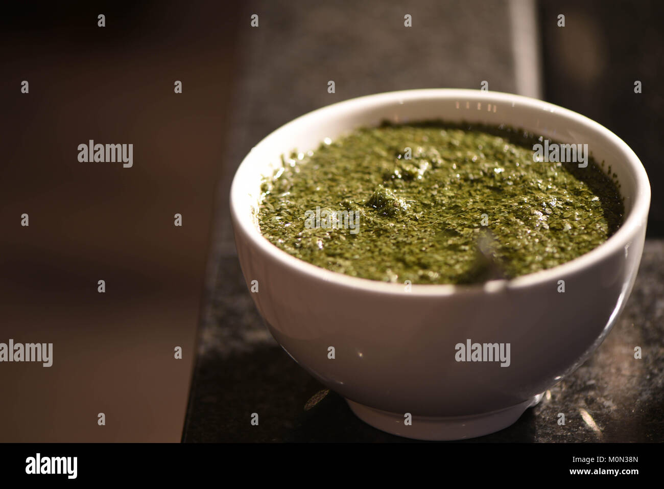 Cibo di fotografia fatta in casa salsa alla menta per un arrosto come un piatto di lato in una ciotola bianco e illuminazione al buio su un sfondo di cucina Foto Stock