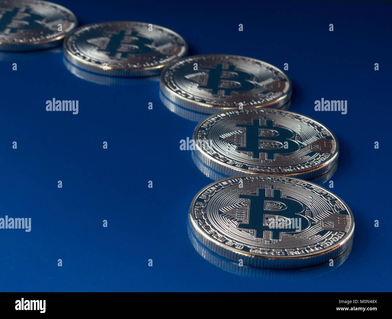 Su uno sfondo blu sono le monete di un digitale valuta crypto bitcoin con testo libero spazio. Sullo sfondo di vetro è un riflesso delle monete. Foto Stock