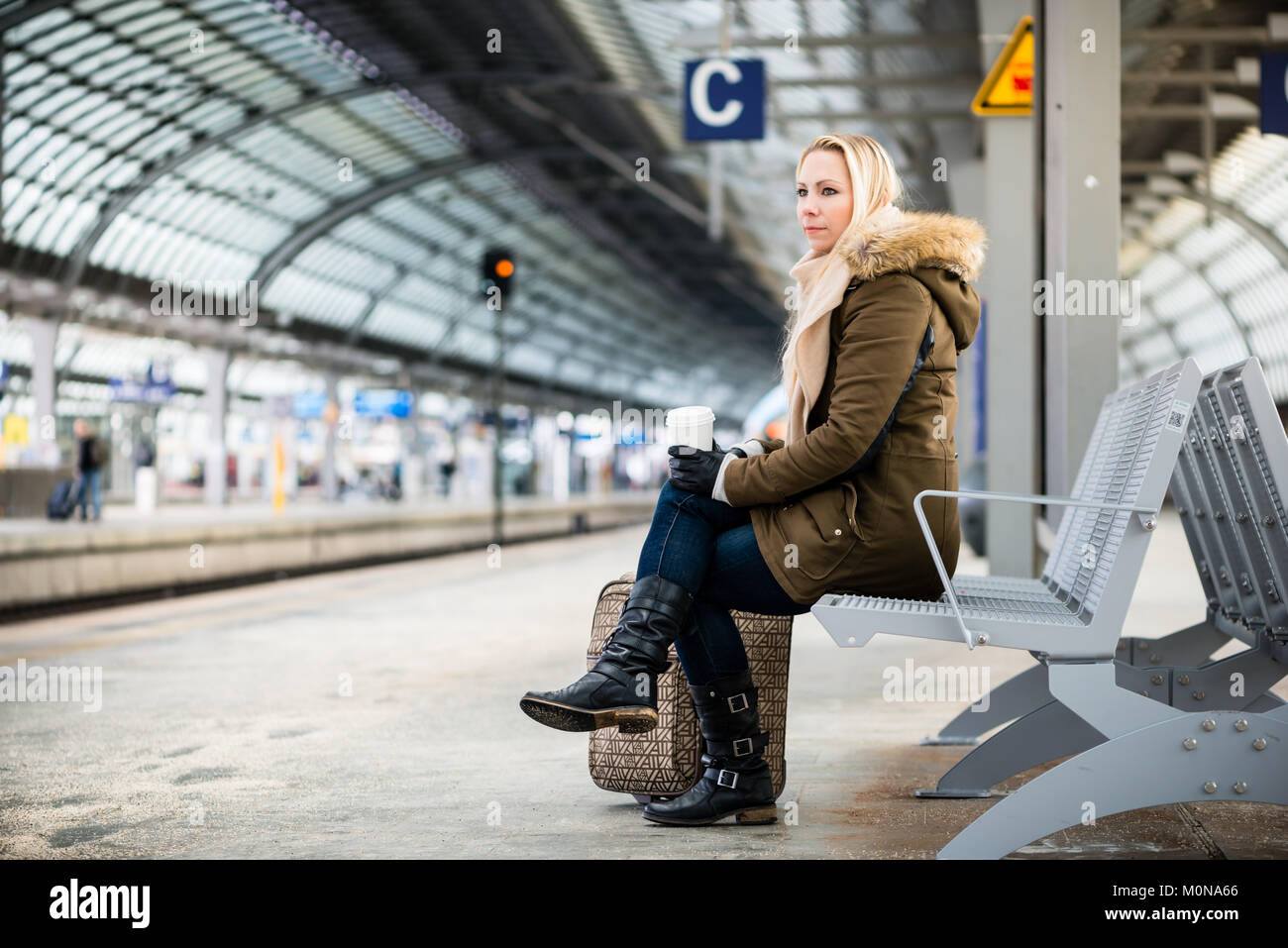 Donna sulla stazione ferroviaria in attesa della piattaforma Foto Stock