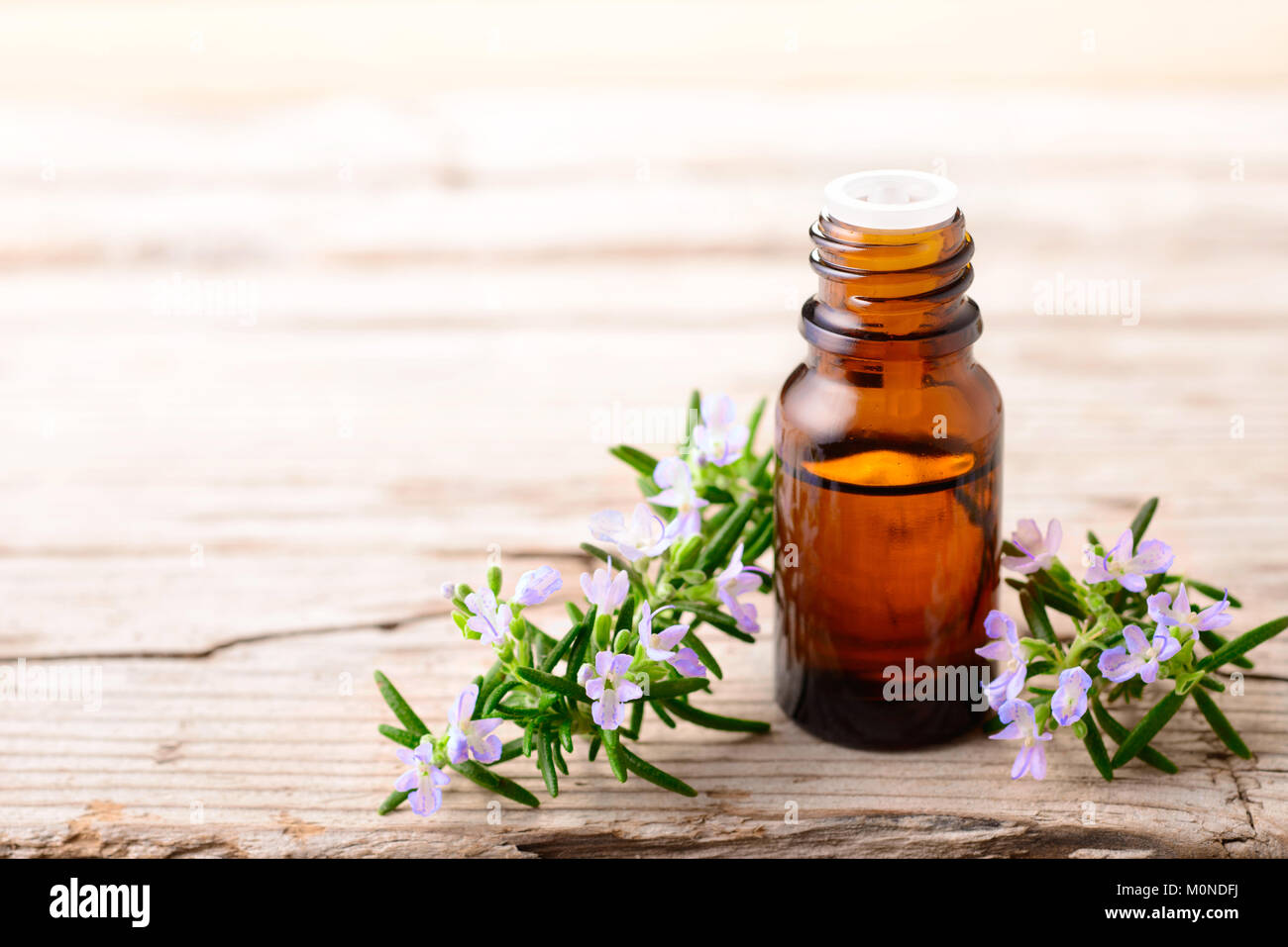 Olio essenziale di rosmarino e fiori sulla tavola di legno Foto Stock