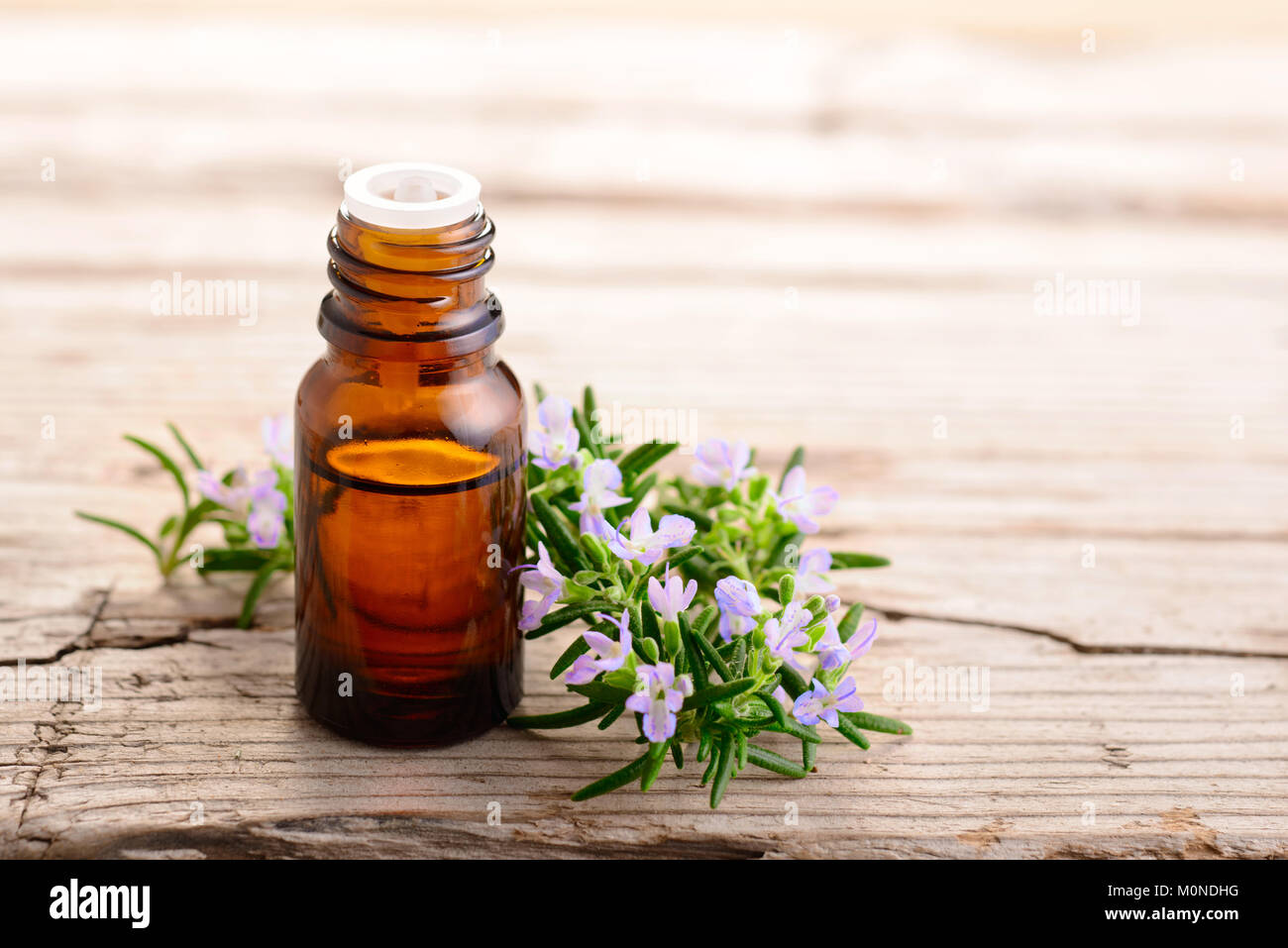 Olio essenziale di rosmarino e fiori sulla tavola di legno Foto Stock