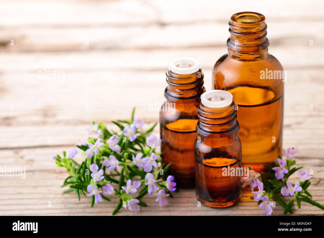 Olio essenziale di rosmarino e fiori sulla tavola di legno Foto Stock