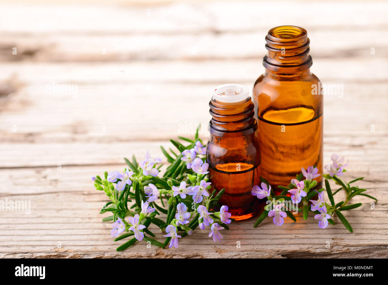 Olio essenziale di rosmarino e fiori sulla tavola di legno Foto Stock