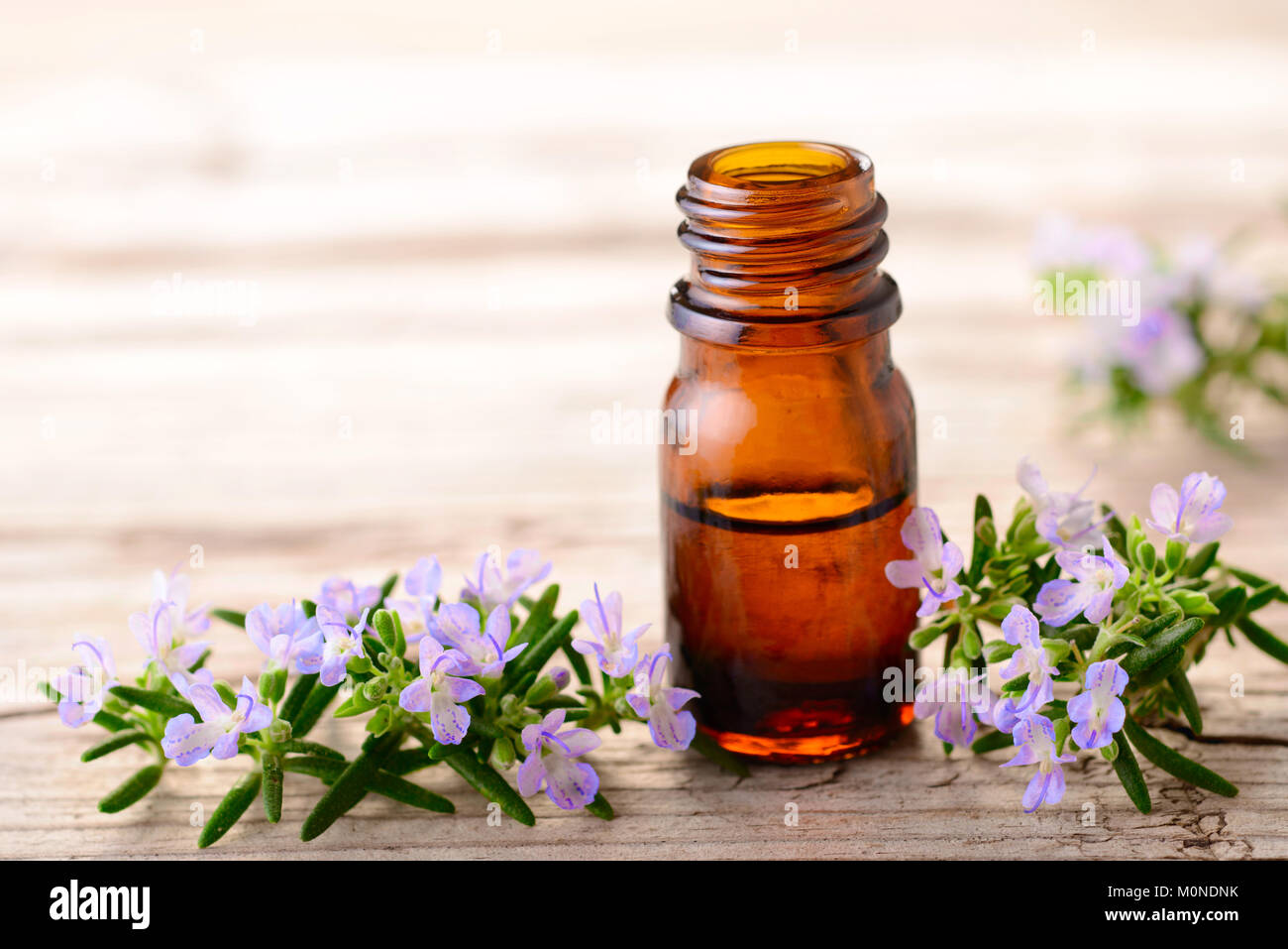 Olio essenziale di rosmarino e fiori sulla tavola di legno Foto Stock