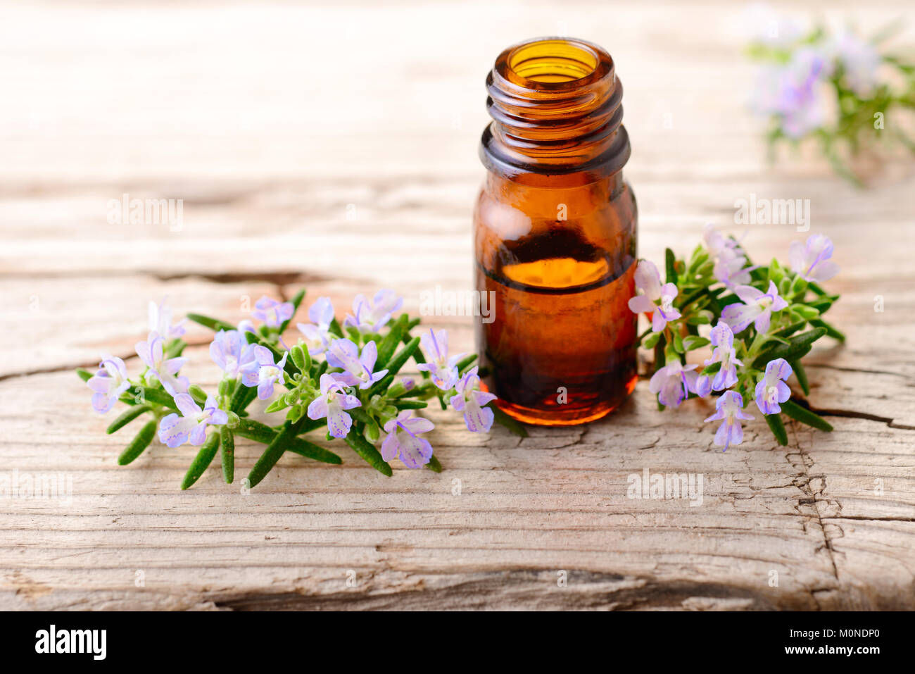 Olio essenziale di rosmarino e fiori sulla tavola di legno Foto Stock