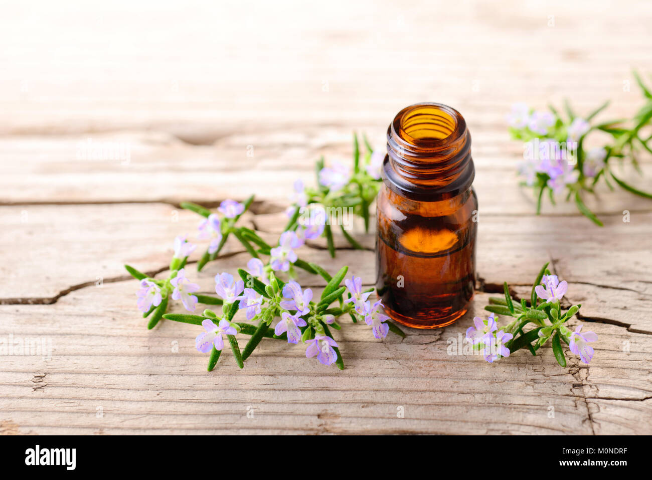 Olio essenziale di rosmarino e fiori sulla tavola di legno Foto Stock