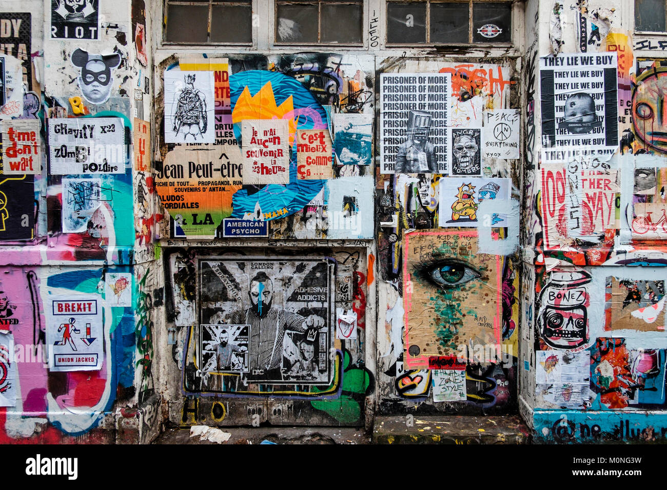 Londra fotografia urbani: Street a parete, coperto con volare poster, Brick Lane, a est di Londra. Foto Stock
