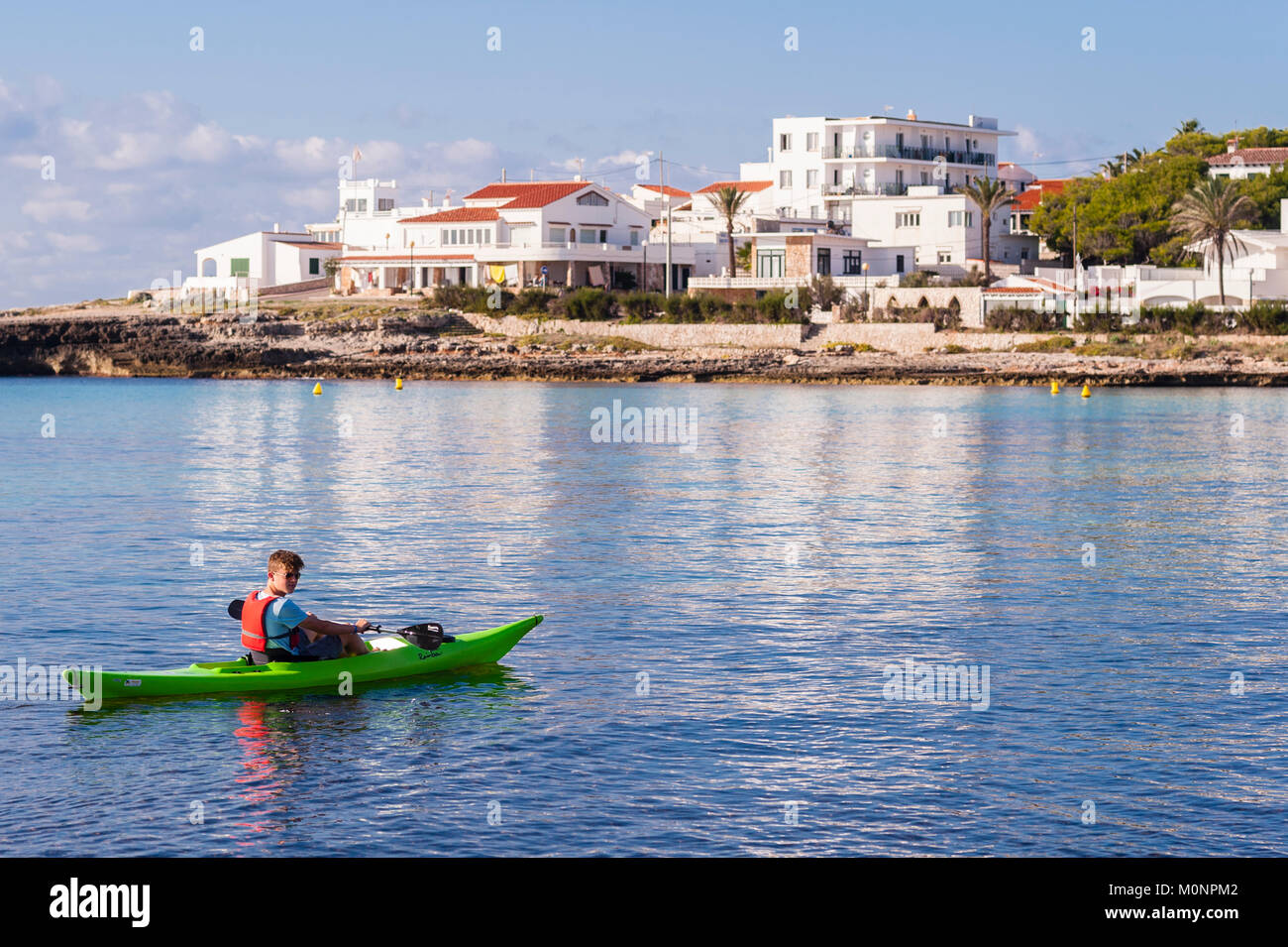 Un ragazzo adolescente in un kayak a Punta Prima , Minorca , Isole Baleari , Spagna Foto Stock