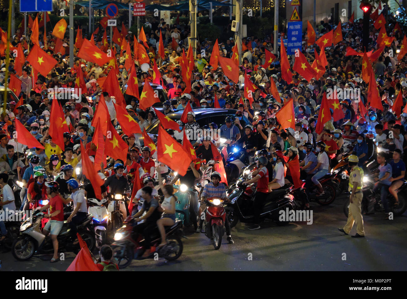 HO CHI MINH CITY, VIET NAM, Folla di calcio vietnamita sostenitore giù in strada per festeggiare la vittoria dopo il calcio di U23 Vietnam, bandiera rossa dai ventilatori Foto Stock
