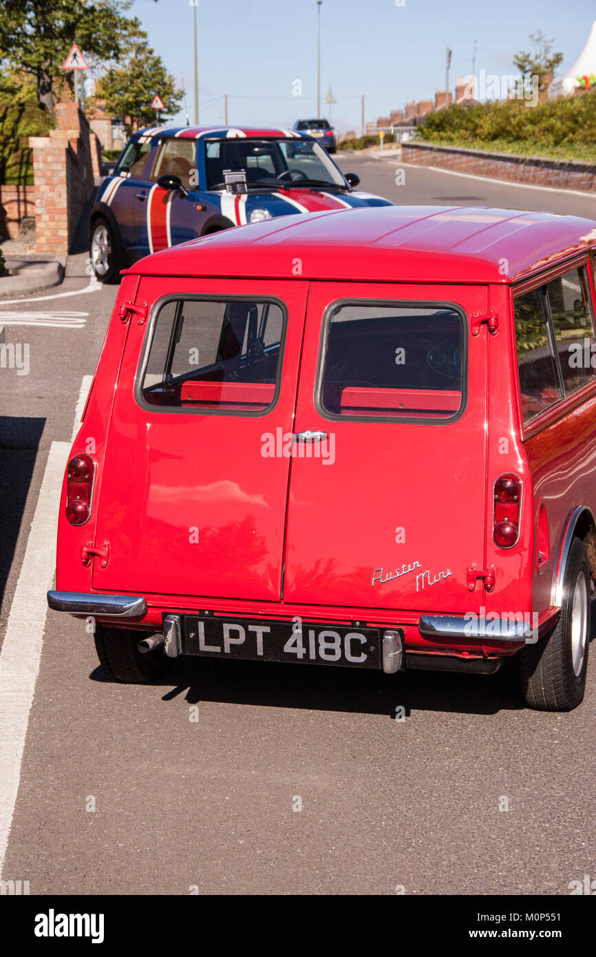 Austin mini station wagon in rosso, con moderne BMW mini in Unione Jack assetto in background Foto Stock