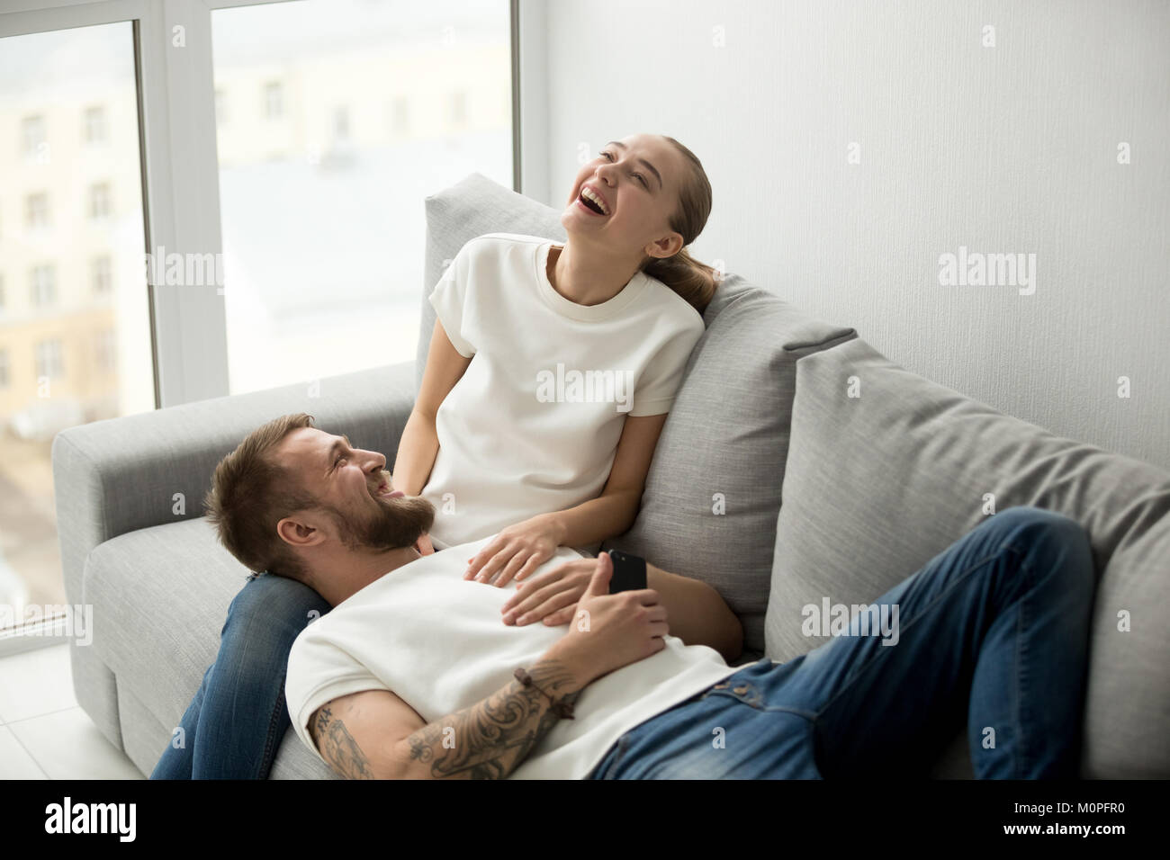 Allegro felice coppia di ridere con gioia in un momento di relax a casa togethe Foto Stock
