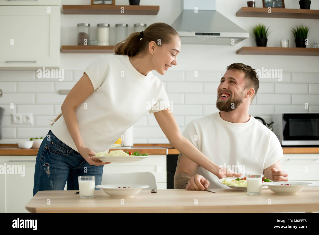 Attraente moglie che serve cibo cucinato per il marito in cucina Foto Stock