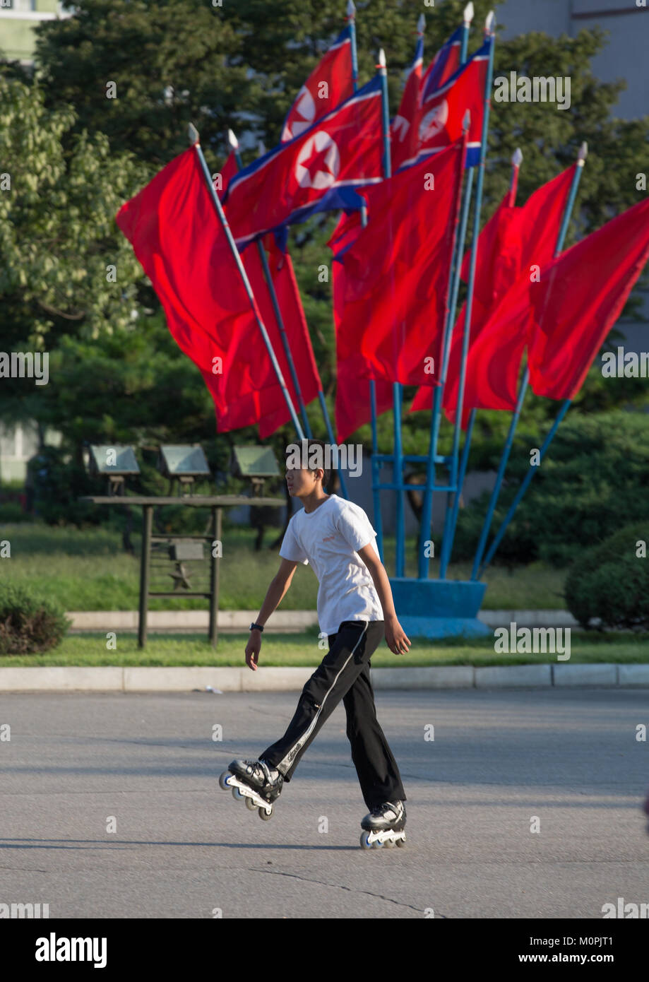 North Korean boy pattinaggio di fronte le bandiere rosse, Provincia di Pyongan, Pyongyang, Corea del Nord Foto Stock