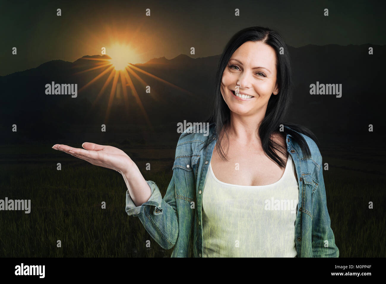 Gioiosa brunette sorridere mentre posa con sun sulla sua mano Foto Stock