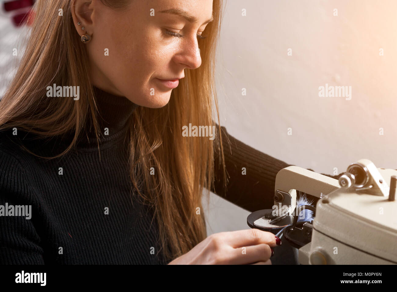 Close up della giovane donna pellicciaio cuce blu pelliccia per donna sulla macchina da cucire in officina Foto Stock