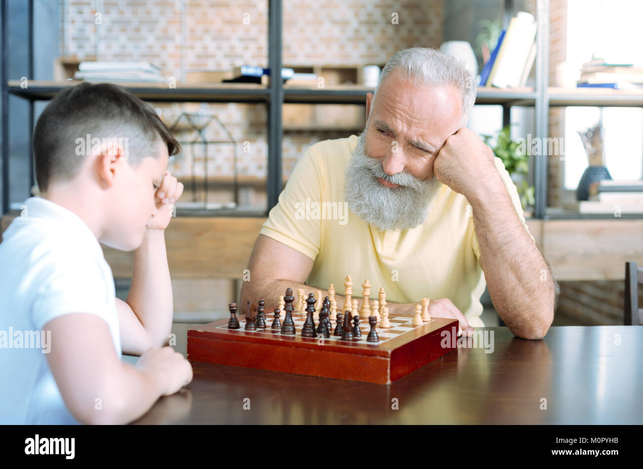 Amare il nonno sorridere mentre guardando il nipote pensando a scacchi Foto Stock