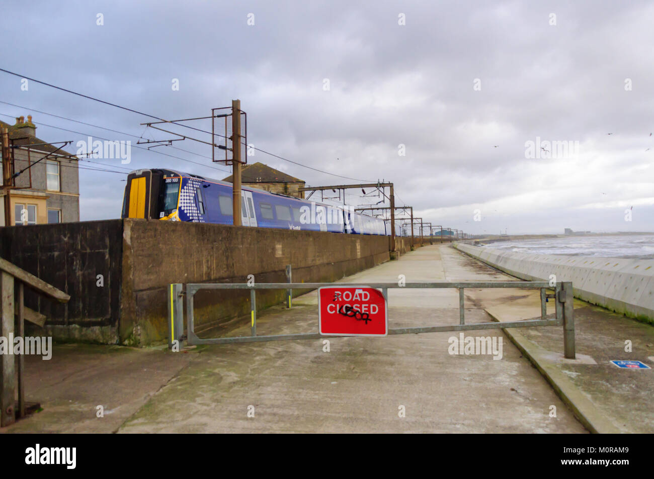 Saltcoats, Scotland, Regno Unito. Il 24 gennaio 2018. Regno Unito Meteo: un treno che passa attraverso Saltcoats viaggi prossima alla linea di costa come alta venti onde causare il crash di contro la parete del mare. La strada è chiusa per motivi di sicurezza. Tempesta Georgina è il settimo denominato storm della stagione ed è previsto per portare alta il vento e la pioggia est spazzando in tutta la Gran Bretagna. Credito: Berretto Alamy/Live News Foto Stock