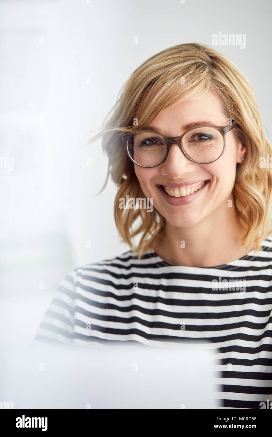 Ritratto di sorridere donna bionda, bicchieri, pc Foto Stock