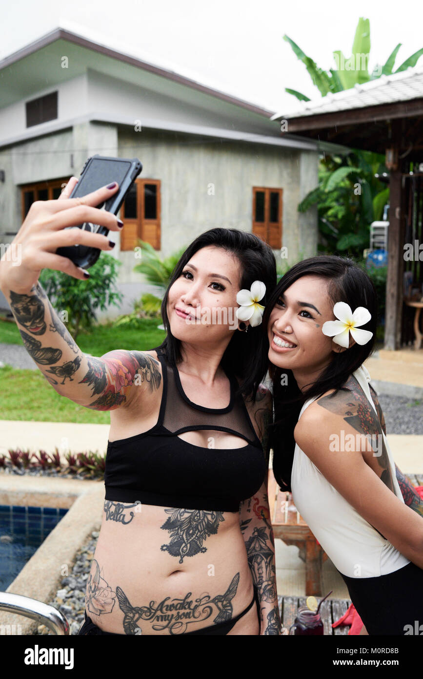Tatuato asian migliori amici gli autoritratti in loro estate villa fiori da indossare. Foto Stock