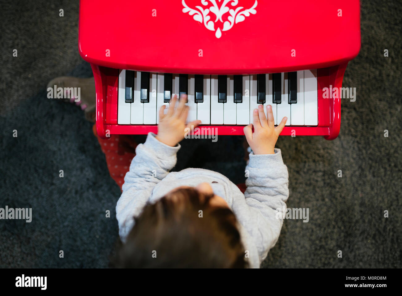 Baby girl suonare il pianoforte giocattolo a casa dal di sopra Foto Stock