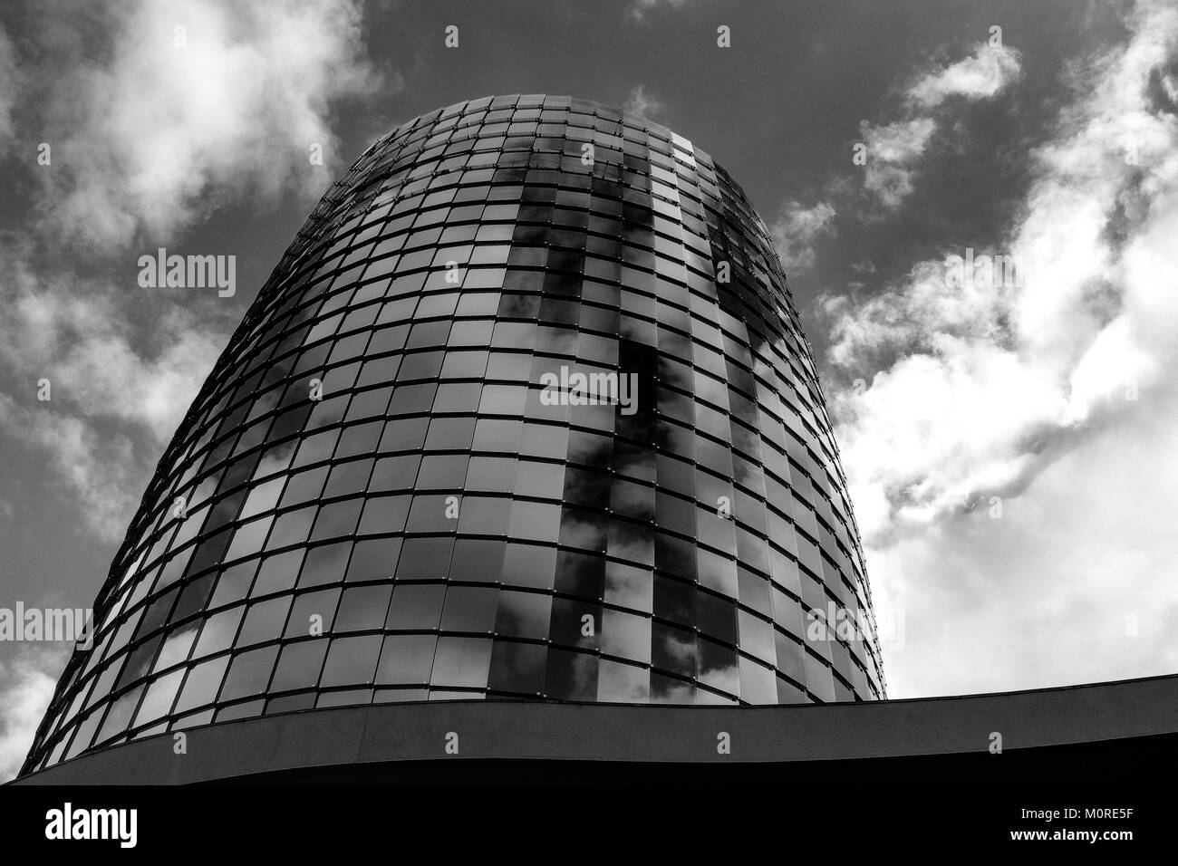 Foto in bianco e nero la focalizzazione su un ufficio moderno edificio circolare in Braga Portogallo, occhiali riflettono le nuvole. Foto Stock