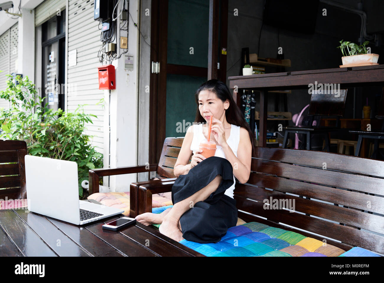 Senior business brunette lady avente un smoothie per la sua pausa di lavoro e guardando il laptop. Foto Stock