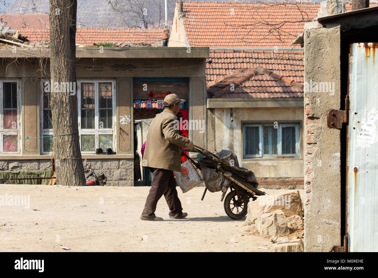 Marzo 2014 - Qingdao, Cina - un uomo trascinando un carrello nel quartiere povero di Shandongtou Foto Stock