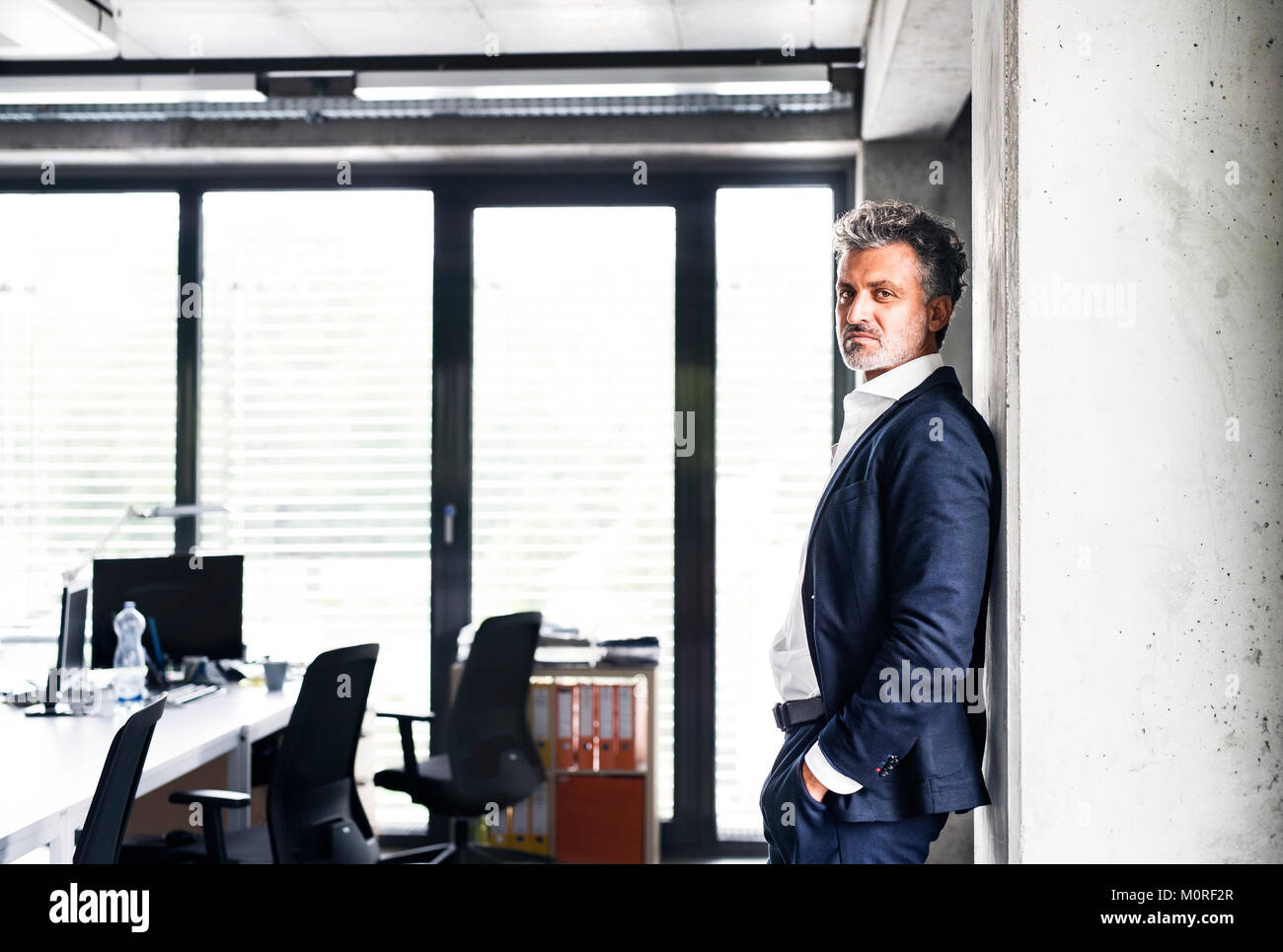 Ritratto di fiducioso imprenditore maturo in piedi in ufficio Foto Stock