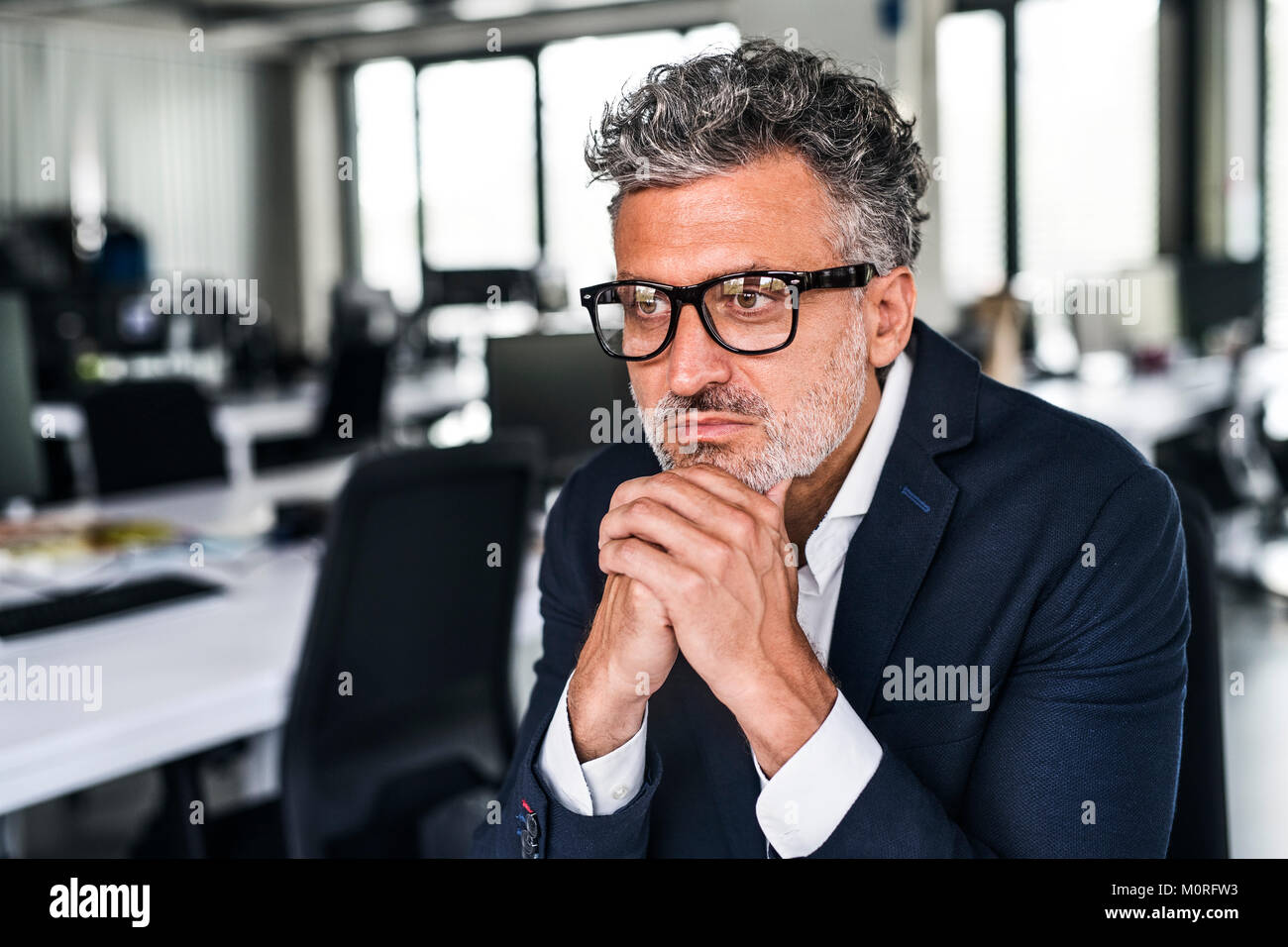 Ritratto di grave imprenditore maturo con gli occhiali in ufficio Foto Stock