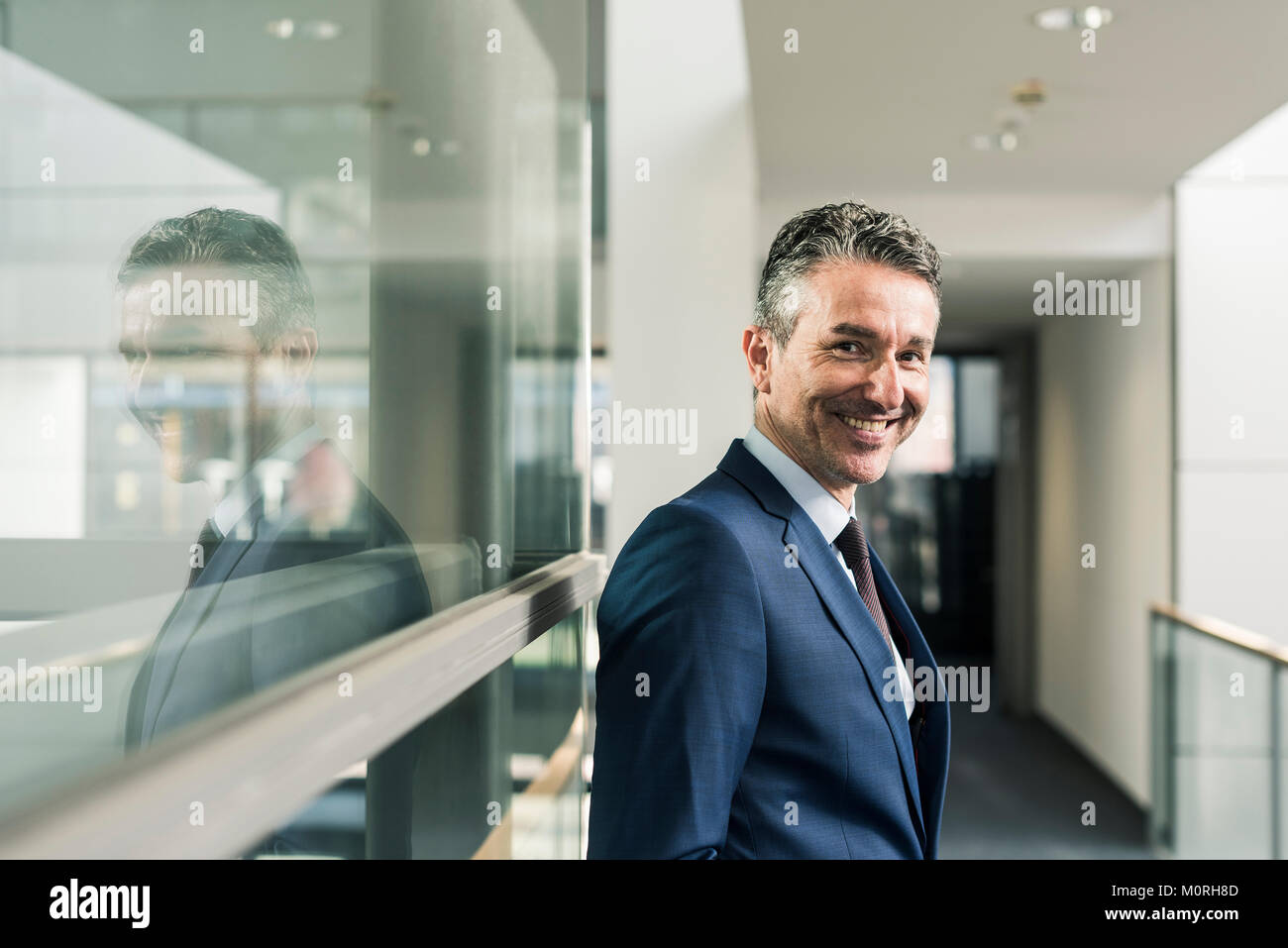 Ritratto di imprenditore sorridente sul pavimento per ufficio Foto Stock